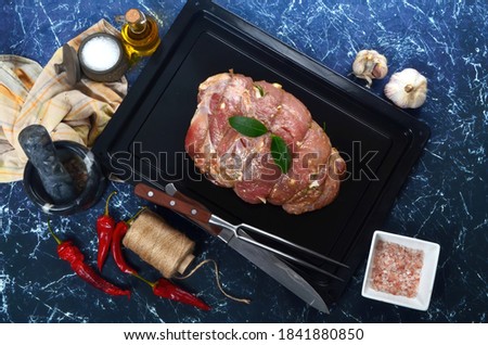 Raw marinated meat on cooking pan, dark stone background, top view. ingredients for roasting
