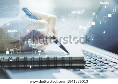 Abstract creative financial graph with world map and with hand writing in diary on background with laptop, financial and trading concept. Multiexposure