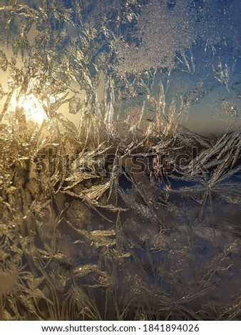 Abstract picture painted by frost on the window and the sun floods pattern with golden light.