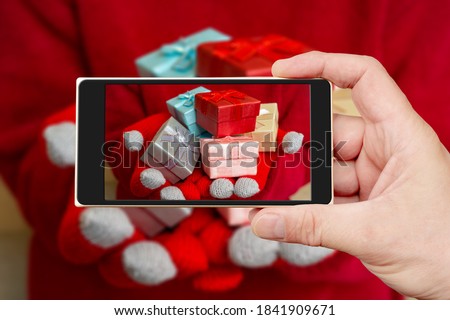 Christmas gift box on the smartphone screen. Festive composition. Red background.