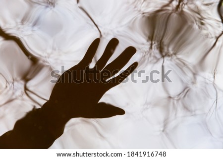 Blurred reflection of a human hand in the water. Abstract background image. The concept of reality testing when practicing lucid dreaming. Shamanism, lucid dreams, reality test. Royalty-Free Stock Photo #1841916748