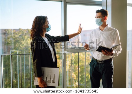 Business woman in protective sterile mask hand showing a stop sign. Stop COVID-19. Business partners back at work in office after quarantine. Meeting near elevator.