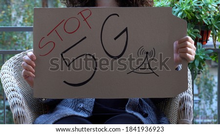 Outdoor portrait of caucasian young woman protest demonstration and flash mob on the balcony during  Covid-19 Coronavirus quarantine home lockdown - Stop 5G wi-fi sign