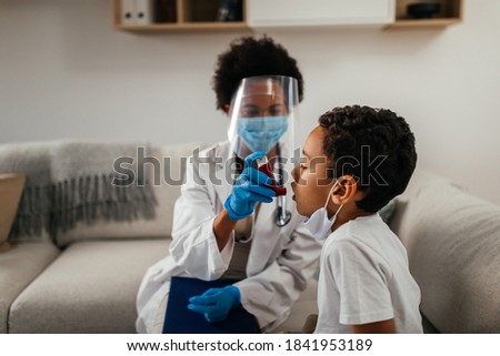 Healthcare worker at home visit. Female doctor is helping little boy to use asthma pump Royalty-Free Stock Photo #1841953189
