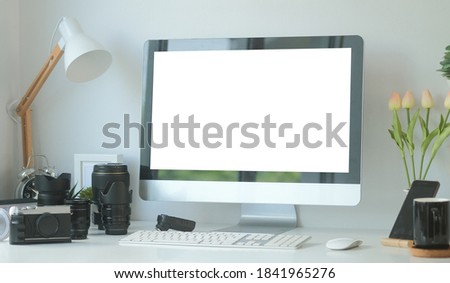 Mock up computer with white screen and medium format camera on designer or photographer table. Photographer or designer workspace.