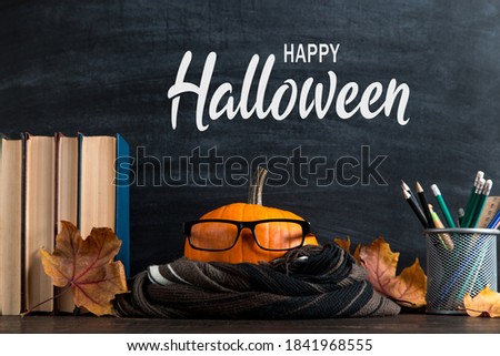 Pumpkin, fallen leaves, scarf, glasses, books and the inscription of happy halloween. The concept of a holiday all saints' eve, greeting card.