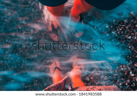 person feet in the sea water on the beach