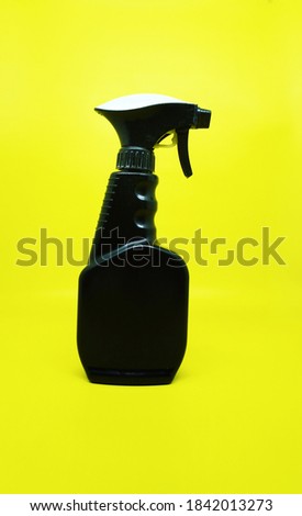 Black plastic bottle with trigger-spray on a yellow background