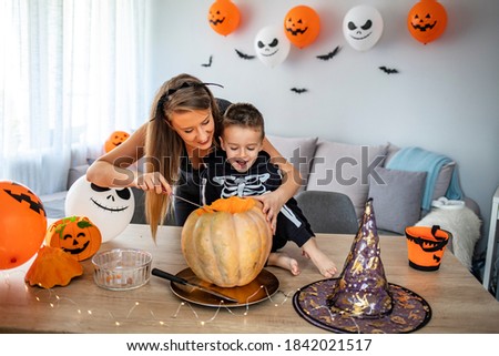 Child and mother in Halloween costume. Kids trick or treat. Little boy dressed as skeleton with pumpkin lantern. Family celebration. Mom and son with pumpkin.