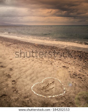 Image of a message of missing love written in sand on a stormy beach. 