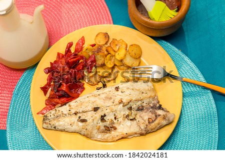 top view of dorada fish fillet with garnish on a yellow plate
