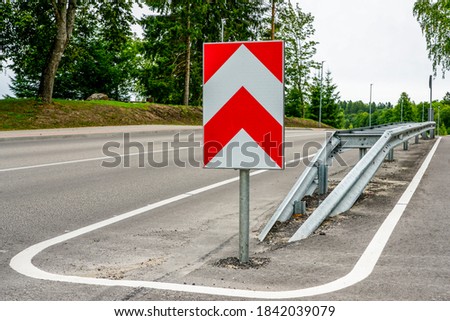 a metal safety barrier with a red and white striped traffic sign