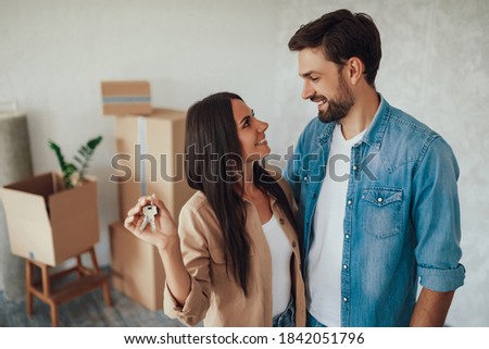 Young brunette lady looking at her male partner with love and affection while holding metal keys from a house Royalty-Free Stock Photo #1842051796