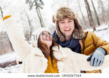 happy loving couple walking in snowy winter forest, spending christmas vacation together. Outdoor seasonal activities
