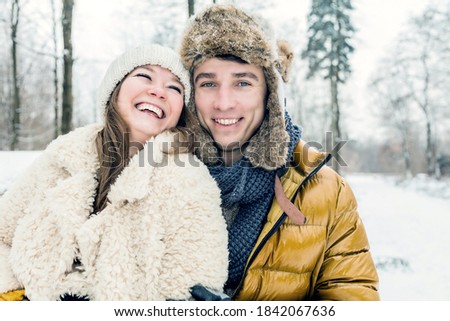 happy loving couple walking in snowy winter forest, spending christmas vacation together. Outdoor seasonal activities