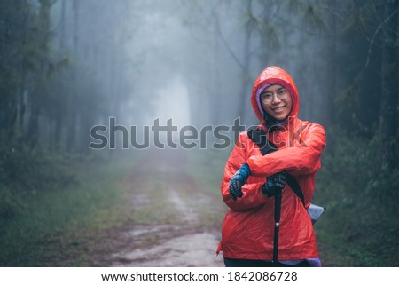 Hipster young girl with enjoying on peak of foggy mountain. Tourist traveler on nature pine forest background