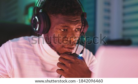 Happy young black man with illuminated headset using laptop. Home office and remote work concept. Stock trader portrait. High quality photo