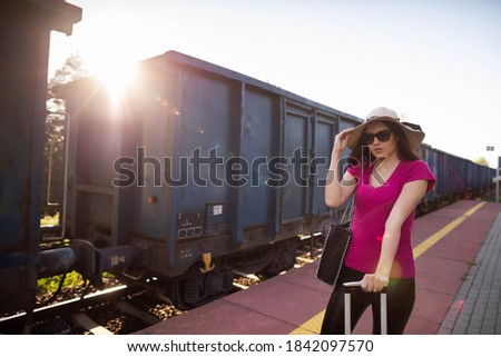 A freight train passes over the platform on which a young adult is standing, making her vacation the most beautiful corners of the world.