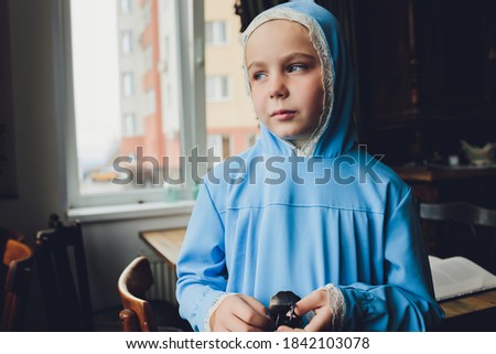 Side portrait of a little Muslim girl wearing a blue hijab. Concept of Muslim clothing for children.