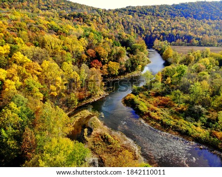 The aerial view of the striking colors of fall foliage by the river near Tunkhannock, Pennsylvania, U.S Royalty-Free Stock Photo #1842110011