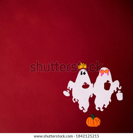 Ghosts in costumes and pumpkins are cut from colored paper on a red background. Square photo of paper art with text for your scary Halloween design.