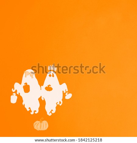 Ghosts and pumpkins are cut from white paper on a orange background. Square photo of paper art for your scary Halloween design. There is a place for text.