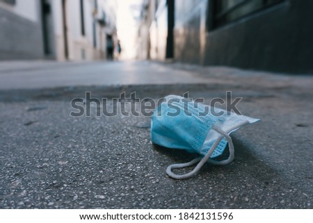 Stock photo of disposable face mask thrown in the floor. Pollution concept. Royalty-Free Stock Photo #1842131596