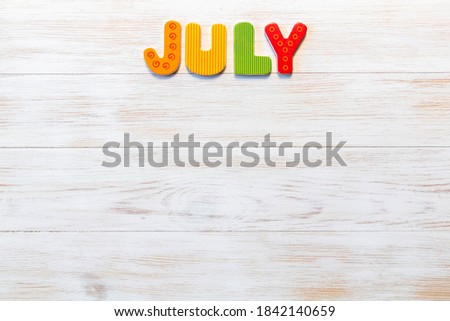 Wooden letters written July month on vintage background. Inscription July with copy space. Top view. Mockup for calendar events. One of 12-month series