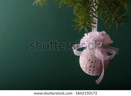 White ball hanging on a Christmas tree branch on a green background. Christmas decorations.
