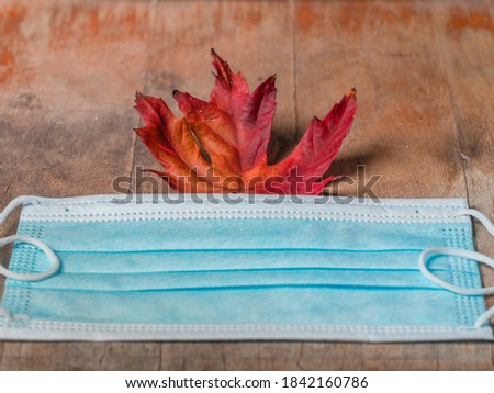 Covid-19 Coronavirus autumn fall  flatlay concep with mask and leaf on wooden board
