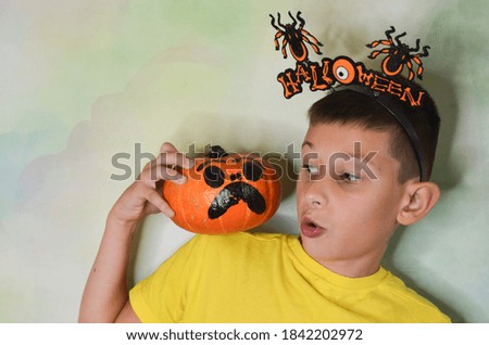 charming teen child isolated on a neutral background in the studio, celebrating the halloween holiday with funny pumpkins lifestyle