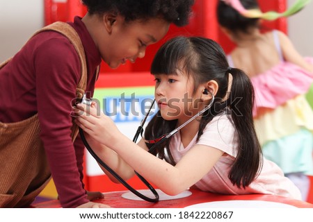 Adorable kid pretending to be doctor, playing funny and holding doctor stethoscope, pretending nurse treating friend as patient.

 Royalty-Free Stock Photo #1842220867