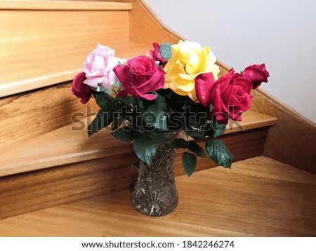 Bouquet of red, pink,  and yellow roses on a timber background