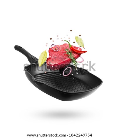 Beef meat flying from a pan with spice and pepper, isolated on white background