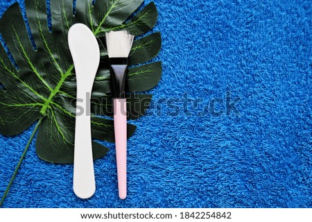 Shovel and brush lie on palm leaf on a background of blue fabric