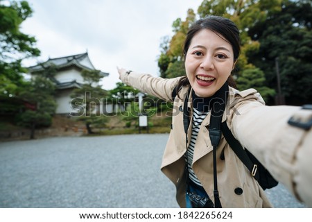 asian travel channel host spreading arm is introducing a cultural heritage in Kyoto to audience. cheerful youtuber is sharing her trip with her followers on arriving at the famous historic site.
