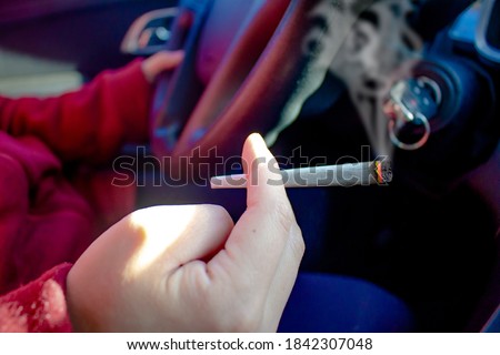 A person with a Cannabis joint smoking and driving. Concept: impaired driving, Driving high, Driving under the influence. Royalty-Free Stock Photo #1842307048