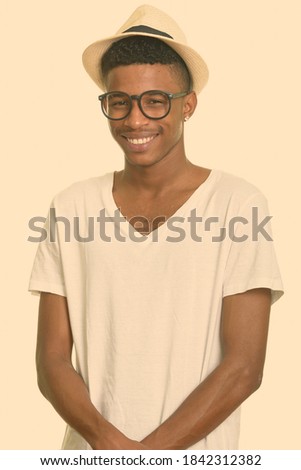 Happy young handsome African tourist man with hat ready for vacation