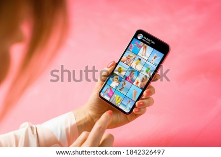 Woman holding phone in hand and browsing looking at other person's photo gallery