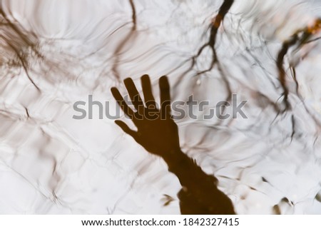 Blurred reflection of a human hand in the water. Abstract background image. The concept of reality testing when practicing lucid dreaming.  Royalty-Free Stock Photo #1842327415