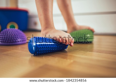 Flat feet correction exercise. Girl using spiked rubber roller