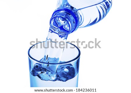 pouring water into the glass from a bottle isolated on white background