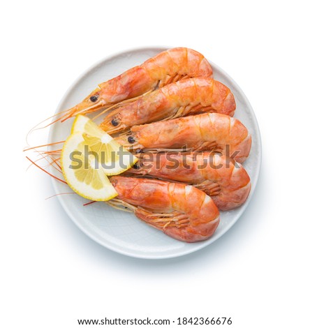 Boiled tiger prawns with lemon on plate isolated on white background. Tasty shrimps.