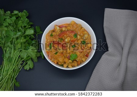 Brazilian fish stew cooked in a delicious, rich and fragrant broth, cilantro, napkin on black baground. Top view.