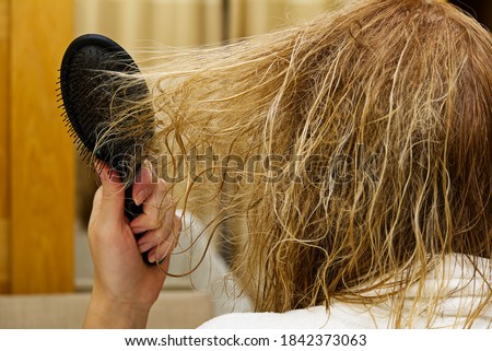 blond combing wet and tangled hair. Young woman combing her tangled hair after shower, close-up. Royalty-Free Stock Photo #1842373063