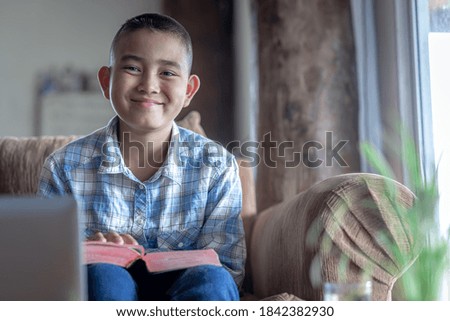 Happy boy in smiling face on sofa with bible, Home church during quarantine coronavirus Covid-19, Religion concept.