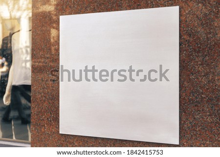 White square signboard on the marble wall of a modern shopping center, mockup