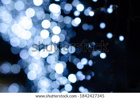 Blurry Christmas lights out of focus background. Bokeh glows on a dark background.Christmas texture for decoration and graphic design for the Christmas