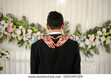 The bride's hand has the picture of hena hugging the groom's shoulder