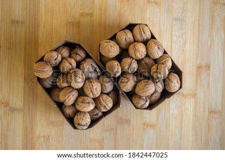 Walnuts on table in hard shells, group of dry ripened fruits in brown cardboard boxes, harvested healthy food ingredients ready for baking and cooking